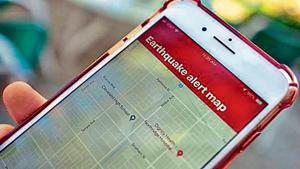 A smartphone user checking an earthquake warning app. A smartphone user checking an earthquake warning app.