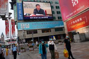 People wearing face masks hold shopping bags as they walk under a giant screen showing a news footage of Chinese President Xi Jinping during a meeting, at a shopping area in Beijing, China.(REUTERS) People wearing face masks hold shopping bags as they walk under a giant screen showing a news footage of Chinese President Xi Jinping during a meeting, at a shopping area in Beijing, China.(REUTERS)