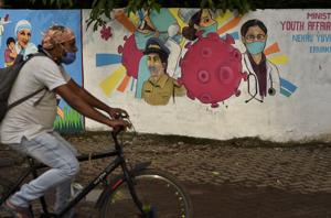 A man wearing a mask pedals his bicycle past a graffiti on a wall made to create awareness about the coronavirus in Kochi, Kerala.(AP) A man wearing a mask pedals his bicycle past a graffiti on a wall made to create awareness about the coronavirus in Kochi, Kerala.(AP)