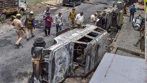 Police and residents walk past charred remains of vehicles vandalised by a mob in Bengaluru last week.(PTI Photo) Police and residents walk past charred remains of vehicles vandalised by a mob in Bengaluru last week.(PTI Photo)