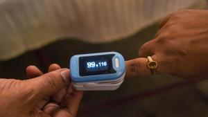 A KMC health worker uses an oximeter on a resident before collecting the sample for Covid-19 test in Kolkata on Sunday.(PTI) A KMC health worker uses an oximeter on a resident before collecting the sample for Covid-19 test in Kolkata on Sunday.(PTI)