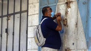 A Palestinian man wears a face mask as he locks a shop during a 48 hour lockdown imposed following the discovery of the first coronavirus cases in the Gaza Strip, Tuesday, Aug. 25, 2020.(AP photo) A Palestinian man wears a face mask as he locks a shop during a 48 hour lockdown imposed following the discovery of the first coronavirus cases in the Gaza Strip, Tuesday, Aug. 25, 2020.(AP photo)