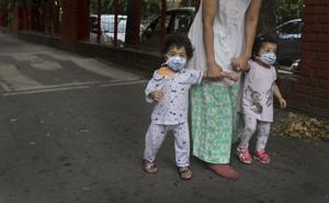A woman takes her toddlers for a walk, their faces covered with masks as a precaution against the coronavirus, in New Delhi.(AP) A woman takes her toddlers for a walk, their faces covered with masks as a precaution against the coronavirus, in New Delhi.(AP)
