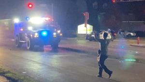 A man with a firearm raises his hands up as he walks towards vehicles during a protest following the police shooting of Jacob Blake, a Black man, in Kenosha, Wisconsin.(Reuters)