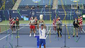 Novak Djokovic, of Serbia, front, holds his winning trophy up high as Milos Raonic, of Canada, center left, looks on after their finals match of the Western & Southern Open tennis tournament Saturday, Aug. 29, 2020, in New York. (AP Photo/Frank Franklin II)(AP) Novak Djokovic, of Serbia, front, holds his winning trophy up high as Milos Raonic, of Canada, center left, looks on after their finals match of the Western & Southern Open tennis tournament Saturday, Aug. 29, 2020, in New York. (AP Photo/Frank Franklin II)(AP)