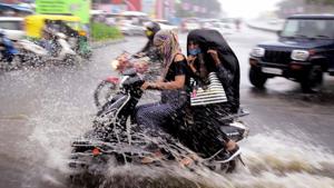 Commuters ride a bike on a waterlogged road during heavy rain in Bhopal.(ANI) Commuters ride a bike on a waterlogged road during heavy rain in Bhopal.(ANI)