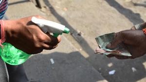A shopkeeper sprays disinfectant on currency notes of a customer after buying liquor from a wine shop at Chander Nagar in East Delhi.(PTI) A shopkeeper sprays disinfectant on currency notes of a customer after buying liquor from a wine shop at Chander Nagar in East Delhi.(PTI)