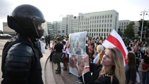 A woman holds a poster with pictures of injured persons in front of a law enforcement officer during a rally against police brutality following protests to reject the presidential election results in Minsk, Belarus.(Reuters File Photo)