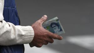 An Iranian money changer holds currency with Ayatollah Ruhollah Khomeini's image in Tehran, Iran.(AP) An Iranian money changer holds currency with Ayatollah Ruhollah Khomeini's image in Tehran, Iran.(AP)
