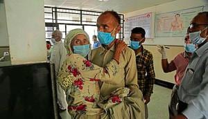 A man carries a woman to have her Covid-19 test done at a government hospital in Jammu on Tuesday.(AP) A man carries a woman to have her Covid-19 test done at a government hospital in Jammu on Tuesday.(AP)