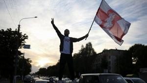 A protester with a historical white-red-white flag of Belarus stands on top of a car during a rally against police brutality following protests to reject the presidential election results in Minsk, Belarus September 13, 2020.(via REUTERS) A protester with a historical white-red-white flag of Belarus stands on top of a car during a rally against police brutality following protests to reject the presidential election results in Minsk, Belarus September 13, 2020.(via REUTERS)
