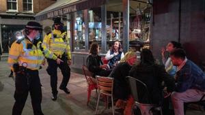 Police chat with drinkers outside a bar in Soho in central London on September 24 on the first day of the new earlier closing times for pubs and bars in England and Wales, introduced to combat the spread of the coronavirus.(AFP) Police chat with drinkers outside a bar in Soho in central London on September 24 on the first day of the new earlier closing times for pubs and bars in England and Wales, introduced to combat the spread of the coronavirus.(AFP)