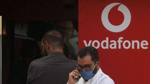 A man wearing a protective face mask talks on his mobile and waits with others outside a branch of Vodafone.(Reuters) A man wearing a protective face mask talks on his mobile and waits with others outside a branch of Vodafone.(Reuters)