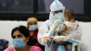 A medical worker in personal protective equipment (PPE) plays with the child of a woman recovering inside a quarantine centre from the coronavirus disease in New Delhi.(REUTERS PHOTO.) A medical worker in personal protective equipment (PPE) plays with the child of a woman recovering inside a quarantine centre from the coronavirus disease in New Delhi.(REUTERS PHOTO.)