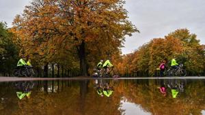 Cyclists ride past trees reflected in a puddle after rainfall in Greenwich Park, London on October 3.(AFP) Cyclists ride past trees reflected in a puddle after rainfall in Greenwich Park, London on October 3.(AFP)