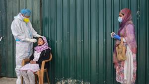 A health worker wearing PPE kit collects sample from a woman for Covid-19 test in Chanpora, Srinagar.(PTI) A health worker wearing PPE kit collects sample from a woman for Covid-19 test in Chanpora, Srinagar.(PTI)