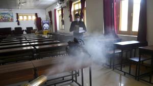 An MCD employee sprays disinfectant inside a classroom after a staffer was tested positive for Covid-19, at a school in Srinagar.(PTI)