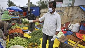 A vegetable vendor wearing gloves and face mask as a precaution against the coronavirus interacts with a customer in Bengaluru.(AP Photo) A vegetable vendor wearing gloves and face mask as a precaution against the coronavirus interacts with a customer in Bengaluru.(AP Photo)
