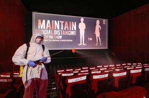 A worker wearing personal protective equipment (PPE) sprays disinfectant inside a cinema hall in Ahmedabad (PTI Photo)(I) A worker wearing personal protective equipment (PPE) sprays disinfectant inside a cinema hall in Ahmedabad (PTI Photo)(I)