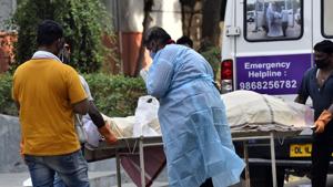 A relative wearing Personal Protective Equipment (PPE) near a handcart carrying the body of a person who died from the Covid-19, at Nigambodh Ghat cremation ground, in New Delhi.(Sanjeev Verma/HT PHOTO) A relative wearing Personal Protective Equipment (PPE) near a handcart carrying the body of a person who died from the Covid-19, at Nigambodh Ghat cremation ground, in New Delhi.(Sanjeev Verma/HT PHOTO)