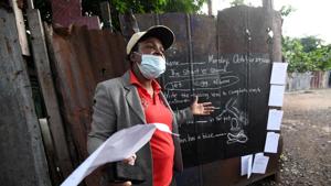 Educator Taneka Mckoy Phipps teaches a lesson next to a blackboard painted on a zinc fence.(REUTERS) Educator Taneka Mckoy Phipps teaches a lesson next to a blackboard painted on a zinc fence.(REUTERS)