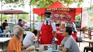 Malaysian former pilot Azrin Mohamad Zawawi talks to customers at his food stall in Subang Jaya, Malaysia November 7, 2020.(REUTERS)
