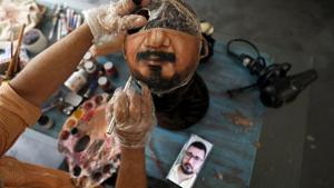 Artist Jorge Silva Roriz paints a customized protective mask looking at man's photo on his phone.(REUTERS) Artist Jorge Silva Roriz paints a customized protective mask looking at man's photo on his phone.(REUTERS)