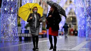 People walk in the rain past Christmas decorations in central London on November 20.(AFP) People walk in the rain past Christmas decorations in central London on November 20.(AFP)