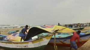 Fishermen cover their boats at Marina Beach during heavy rain, triggered by Cyclone Nivar,in Chennai on Tuesday.(PTI Photo) Fishermen cover their boats at Marina Beach during heavy rain, triggered by Cyclone Nivar,in Chennai on Tuesday.(PTI Photo)