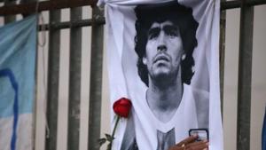 A rose is placed next to a banner of Argentine soccer great Diego Maradona.(Reuters) A rose is placed next to a banner of Argentine soccer great Diego Maradona.(Reuters)