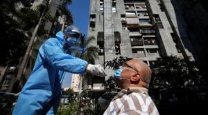 A healthcare worker wearing personal protective equipment (PPE) takes a swab from a man during a testing campaign for the coronavirus disease at a residential area in Ahmedabad.(REUTERS) A healthcare worker wearing personal protective equipment (PPE) takes a swab from a man during a testing campaign for the coronavirus disease at a residential area in Ahmedabad.(REUTERS)