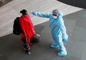 A health worker in personal protective equipment (PPE) checks the temperature of a passenger at a railway station, amid the spread of the coronavirus disease (COVID-19), in Mumbai, on November 27.(REUTERS) A health worker in personal protective equipment (PPE) checks the temperature of a passenger at a railway station, amid the spread of the coronavirus disease (COVID-19), in Mumbai, on November 27.(REUTERS)