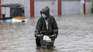A man wearing a mask as a precaution against Covid-19 pedals his cycle through a flooded street in Chennai last week.(AP Photo) A man wearing a mask as a precaution against Covid-19 pedals his cycle through a flooded street in Chennai last week.(AP Photo)