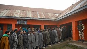 Indian paramilitary soldiers stand guard as voters stand in queues to cast their ballots during the District Development Council (DDC) and Panchayat by-elections in Jammu and Kashmir.(AFP)