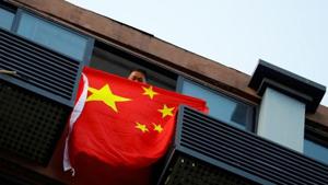 A man holds a Chinese flag from a house opposite the US Consulate General in Chengdu, Sichuan province.(REUTERS) A man holds a Chinese flag from a house opposite the US Consulate General in Chengdu, Sichuan province.(REUTERS)