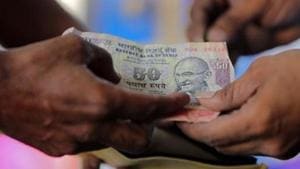 A customer hands a 50-Indian rupee note to an attendant at a fuel station in Ahmedabad.(Reuters) A customer hands a 50-Indian rupee note to an attendant at a fuel station in Ahmedabad.(Reuters)