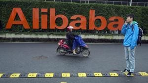In this file photo, a man talks on his phone as a woman rides on an electric bike past a company logo at the Alibaba Group headquarters in Hangzhou in eastern China's Zhejiang province. China’s market regulator on Monday, Dec. 14, 2020 said it fined Alibaba Group and a Tencent Holdings-backed company for failing to seek approval before proceeding with some acquisitions. (AP Photo/Ng Han Guan, File) In this file photo, a man talks on his phone as a woman rides on an electric bike past a company logo at the Alibaba Group headquarters in Hangzhou in eastern China's Zhejiang province. China’s market regulator on Monday, Dec. 14, 2020 said it fined Alibaba Group and a Tencent Holdings-backed company for failing to seek approval before proceeding with some acquisitions. (AP Photo/Ng Han Guan, File)