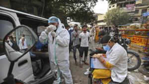 A health worker gets ready to take samples from people to test for Covid-19 as another registers them at a marketplace in New Delhi.(AP) A health worker gets ready to take samples from people to test for Covid-19 as another registers them at a marketplace in New Delhi.(AP)