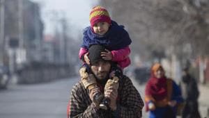 A Kashmiri man carries his child on shoulders and walks with other family members towards a bus terminal on a cold day in Srinagar.(AP) A Kashmiri man carries his child on shoulders and walks with other family members towards a bus terminal on a cold day in Srinagar.(AP)
