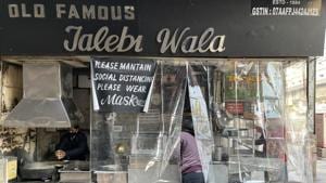 The legendary Old Famous Jalebi Wala shop in Chandni Chowk is screened off with a plastic curtain on an early December morning. A special poster cane up three weeks ago asking customers to maintain social distancing. The masked cook, Vicky, has just finished deep-frying the day’s first batch of jalebis. The shop stayed closed for two months during the lockdown and reopened in early June. (Mayank Austen Soofi / HT Photo) The legendary Old Famous Jalebi Wala shop in Chandni Chowk is screened off with a plastic curtain on an early December morning. A special poster cane up three weeks ago asking customers to maintain social distancing. The masked cook, Vicky, has just finished deep-frying the day’s first batch of jalebis. The shop stayed closed for two months during the lockdown and reopened in early June. (Mayank Austen Soofi / HT Photo)