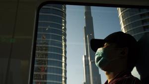 FILE - In this April 26, 2020 file photo, a commuter wearing a face mask to help curb the spread of the coronavirus, sleeps aboard the driverless Metro as it passes the Burj Khalifa, the world's tallest building, in Dubai, United Arab Emirates (AP Photo/Jon Gambrell, File) FILE - In this April 26, 2020 file photo, a commuter wearing a face mask to help curb the spread of the coronavirus, sleeps aboard the driverless Metro as it passes the Burj Khalifa, the world's tallest building, in Dubai, United Arab Emirates (AP Photo/Jon Gambrell, File)