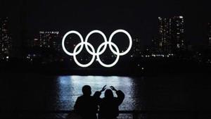 FILE - In this Dec. 1, 2020, file photo, a man and a woman look at the Olympic rings float in the water(AP)