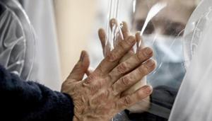 Relatives touch each other's hand through a plastic film screen and a glass to avoid contracting Covid-19 at the San Raffaele center in Rome.(AP) Relatives touch each other's hand through a plastic film screen and a glass to avoid contracting Covid-19 at the San Raffaele center in Rome.(AP)