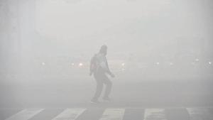 A man crosses the road at Tilak Marg, near ITO, on Friday when the capital witnessed dense fog.(Arvind Yadav/HT PHOTO)