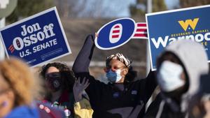 People wave signs during a rally for Democratic Georgia Senate challengers the Rev. Raphael Warnock and Jon Ossoff in Atlanta.(AP) People wave signs during a rally for Democratic Georgia Senate challengers the Rev. Raphael Warnock and Jon Ossoff in Atlanta.(AP)