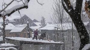 Men clear snow from the roof of their workshop as it snows in Pulwama, south of Srinagar, Kashmir, Monday.(AP) Men clear snow from the roof of their workshop as it snows in Pulwama, south of Srinagar, Kashmir, Monday.(AP)