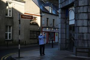 A woman wearing a protective face mask takes a photo of the empty city centre shopping street after the government imposed the highest level of restrictions amid the spread of the coronavirus disease (Covid-19) pandemic, in Galway, Ireland.(Reuters) A woman wearing a protective face mask takes a photo of the empty city centre shopping street after the government imposed the highest level of restrictions amid the spread of the coronavirus disease (Covid-19) pandemic, in Galway, Ireland.(Reuters)