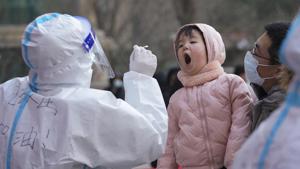A medical staff in a protective suit prepares to take a swab from a child near a residential area in Shijiazhuang in north China's Hebei province.(AP) A medical staff in a protective suit prepares to take a swab from a child near a residential area in Shijiazhuang in north China's Hebei province.(AP)