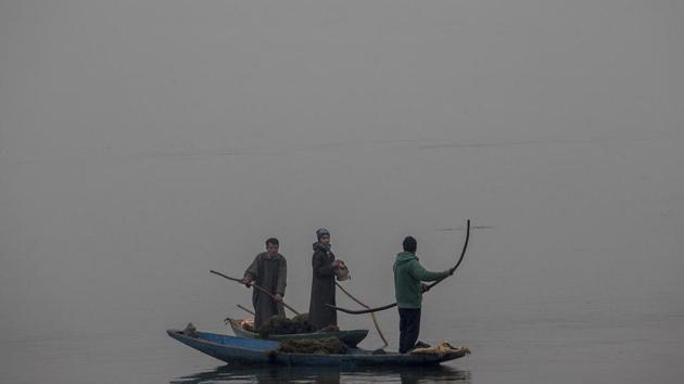 A Kashmiri worker warms his hands on a Kangri or traditional fire pot as he takes break from removing weed on a cold and foggy day at the Dal Lake in Srinagar. Cold conditions continued in most parts of Kashmir with fog affecting air traffic and normal life. (AP)