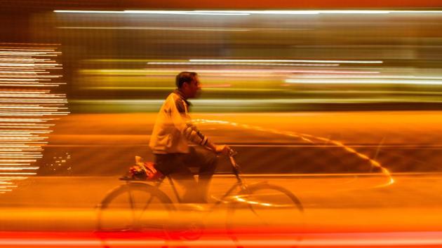 A man cycles on a brightly-lit road on a foggy evening in Amritsar. (Gurpreet Singh/HT)